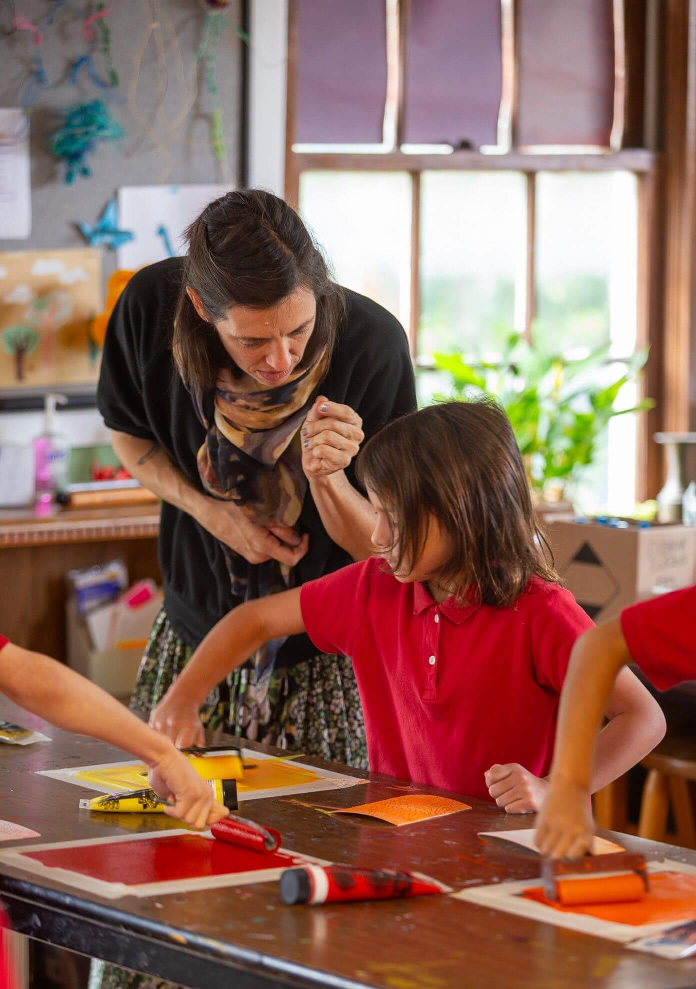 Teacher assisting young students with art projects in a classroom setting, fostering creativity and learning.